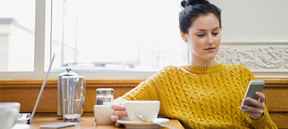 Mujer joven sentada en un café mirando un teléfono