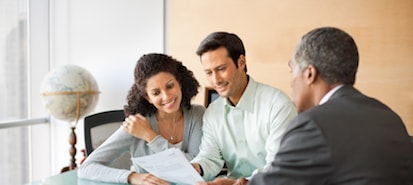 Couple Seated at a Table Reading a Report with their Financial Advisor